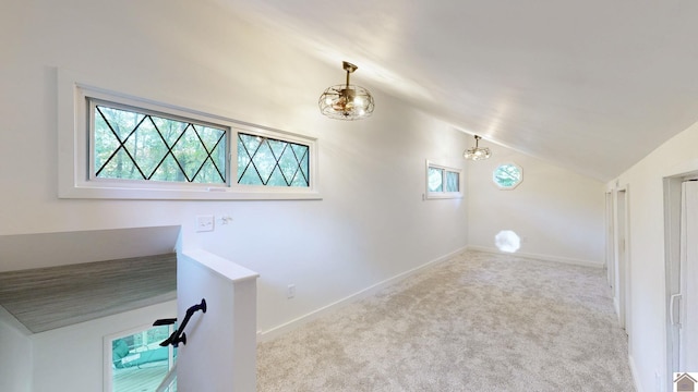 interior space featuring light carpet, a healthy amount of sunlight, and vaulted ceiling