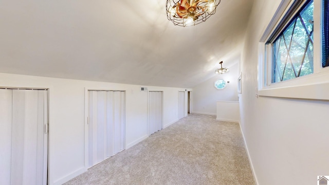 hallway featuring light carpet and vaulted ceiling