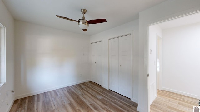 unfurnished bedroom featuring light hardwood / wood-style floors, two closets, and ceiling fan