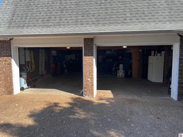 garage featuring electric panel and white refrigerator