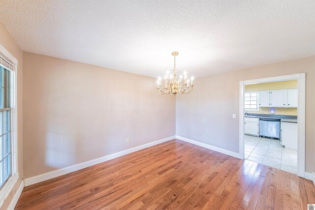 9618 Scale Rd, Benton, KY 42025 - empty room with baseboards, a chandelier, light wood finished floors, and a textured ceiling