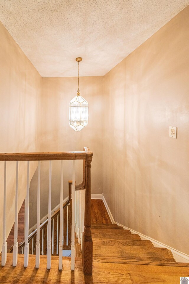 9618 Scale Rd, Benton, KY 42025 - stairway featuring baseboards, a notable chandelier, wood finished floors, and a textured ceiling
