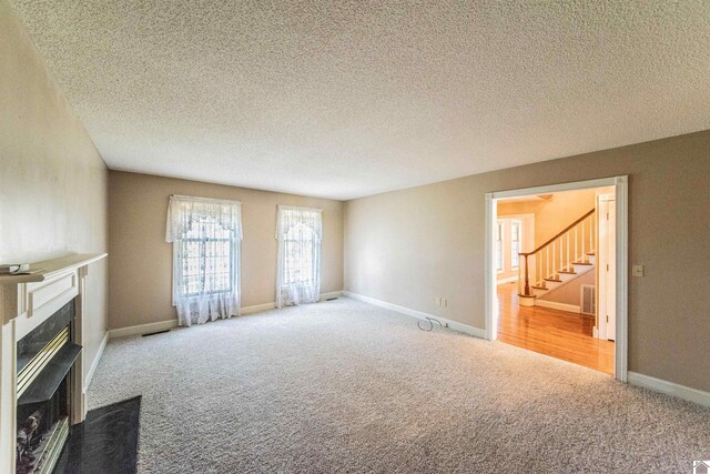 9618 Scale Rd, Benton, KY 42025 - unfurnished living room with stairway, a textured ceiling, a fireplace with flush hearth, carpet flooring, and visible vents