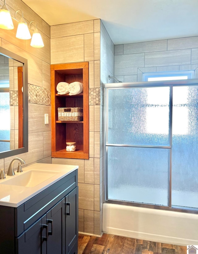 bathroom with vanity, enclosed tub / shower combo, hardwood / wood-style flooring, and a wealth of natural light