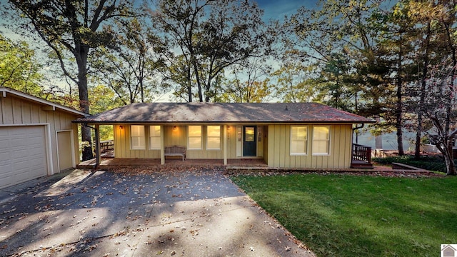 ranch-style house featuring covered porch, a front yard, and a garage