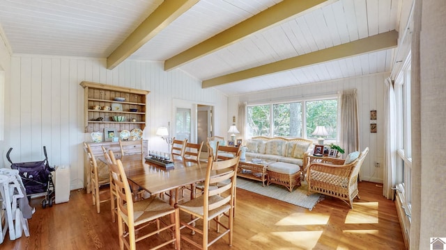 dining area featuring wood walls, lofted ceiling with beams, and light wood-type flooring