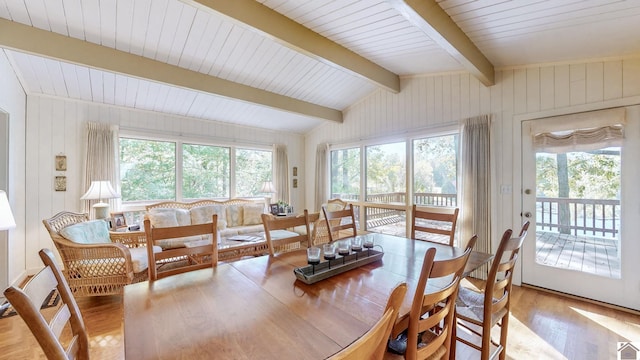 dining area with lofted ceiling with beams, light wood-type flooring, and wood walls