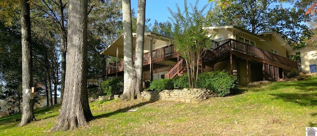 rear view of house featuring a wooden deck and a lawn