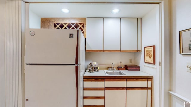 kitchen with white fridge, sink, and white cabinets