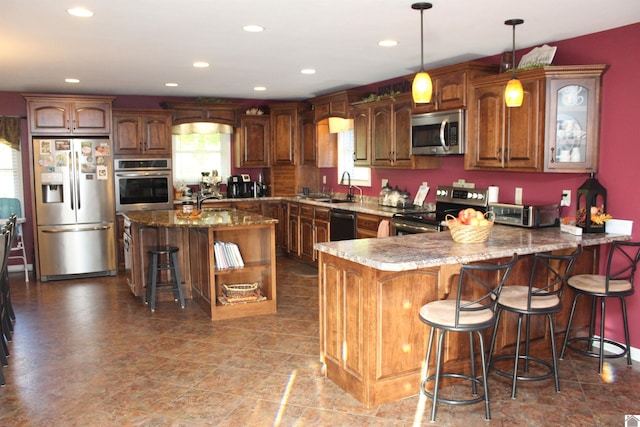 kitchen with hanging light fixtures, a kitchen island, a kitchen bar, sink, and stainless steel appliances