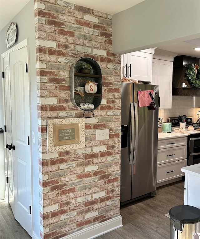 kitchen featuring tasteful backsplash, wall chimney range hood, dark hardwood / wood-style flooring, stainless steel appliances, and white cabinets