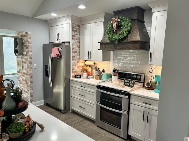 kitchen with white cabinetry, stainless steel appliances, decorative backsplash, premium range hood, and dark hardwood / wood-style floors