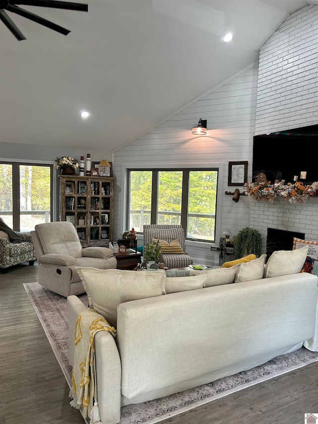 living room with wood walls, vaulted ceiling, a brick fireplace, and dark hardwood / wood-style flooring