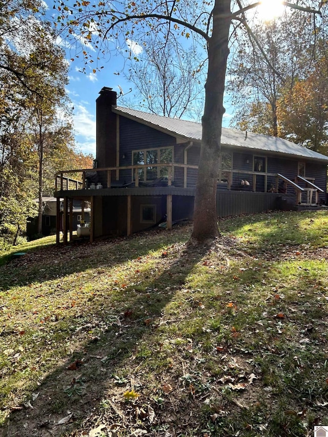 back of property featuring a wooden deck and a yard