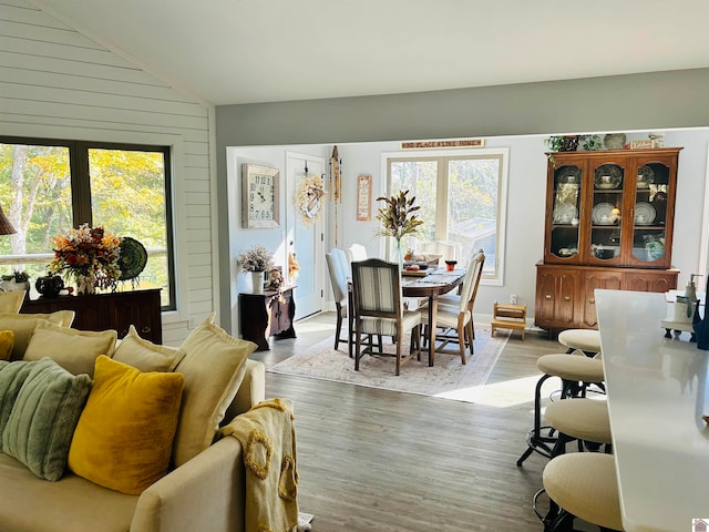 living room featuring lofted ceiling, wooden walls, and light wood-type flooring