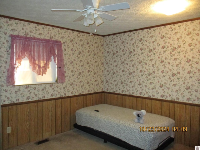 bedroom with wood walls, a textured ceiling, and ceiling fan