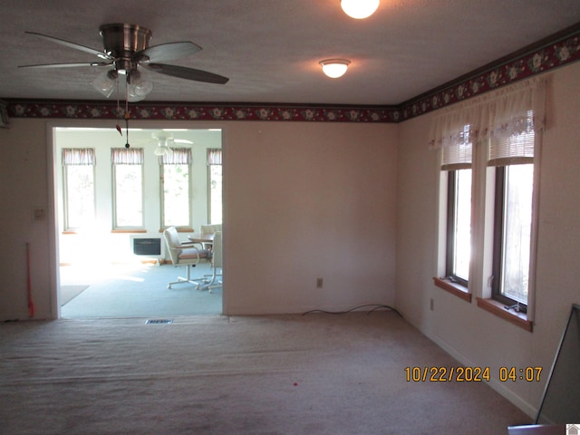 unfurnished room with a wealth of natural light, an AC wall unit, carpet floors, and ceiling fan