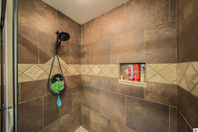 bathroom with a textured ceiling and tiled shower