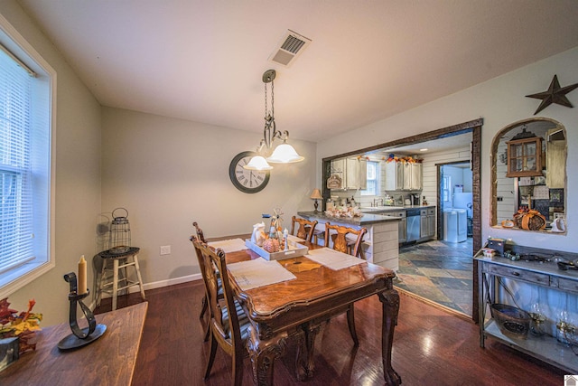 dining room featuring an inviting chandelier, a healthy amount of sunlight, and dark hardwood / wood-style flooring