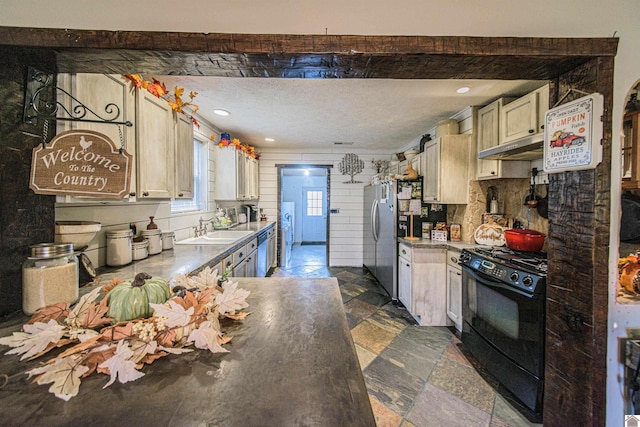 kitchen featuring a textured ceiling, sink, black range oven, and dishwasher