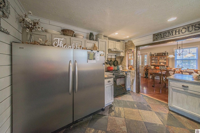 kitchen with a textured ceiling, stainless steel fridge, pendant lighting, black range with gas cooktop, and a chandelier