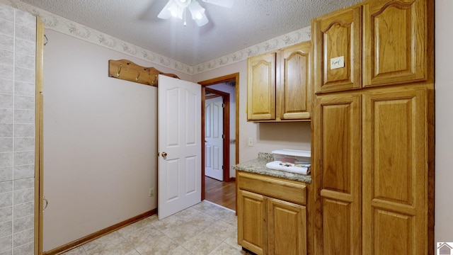 interior space featuring baseboards, a textured ceiling, ceiling fan, and light tile patterned floors