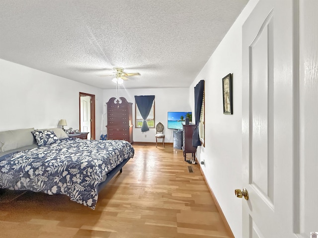 bedroom with light wood-style floors, baseboards, ceiling fan, and a textured ceiling