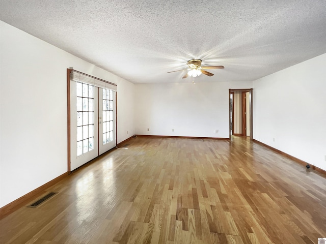 empty room with visible vents, light wood finished floors, ceiling fan, and baseboards