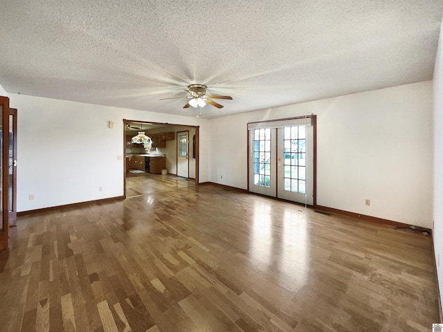 unfurnished room with a textured ceiling, ceiling fan, baseboards, and wood finished floors