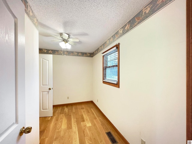 unfurnished room with a textured ceiling, light wood-type flooring, and ceiling fan