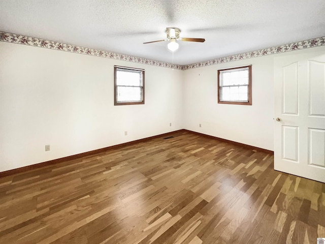 unfurnished bedroom with ceiling fan, baseboards, multiple windows, and wood finished floors
