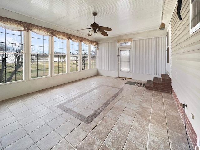 unfurnished sunroom featuring ceiling fan and a wealth of natural light