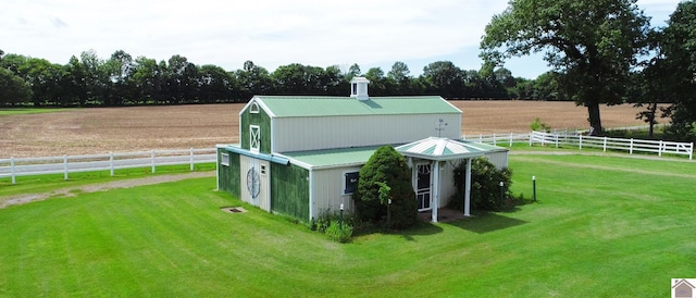 view of outdoor structure with fence, an outbuilding, and a rural view