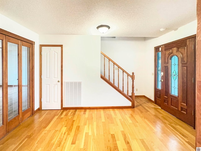 entryway with wood-type flooring and a textured ceiling