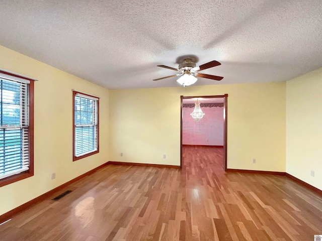 empty room featuring ceiling fan, a textured ceiling, light wood-type flooring, and plenty of natural light