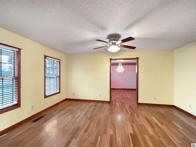 unfurnished room with visible vents, wood finished floors, baseboards, a textured ceiling, and a ceiling fan