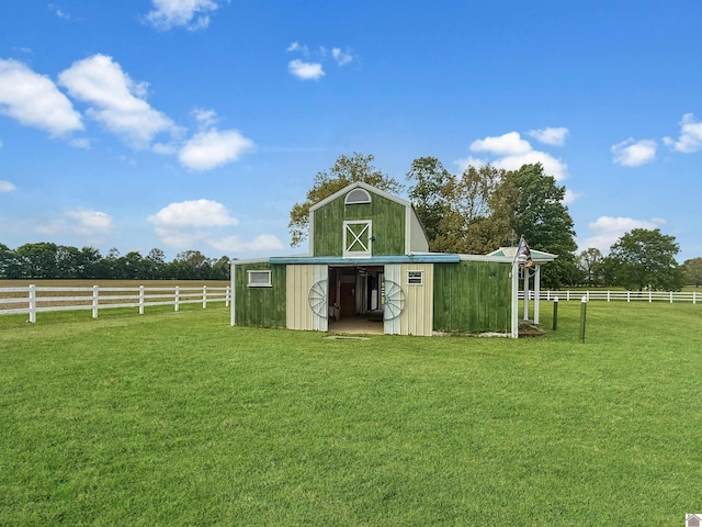 view of barn featuring fence and a yard