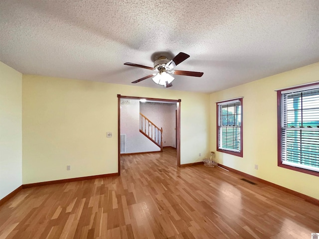 empty room featuring light hardwood / wood-style flooring, a textured ceiling, and ceiling fan