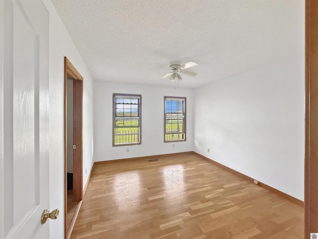 unfurnished room with baseboards, ceiling fan, light wood-type flooring, and a textured ceiling