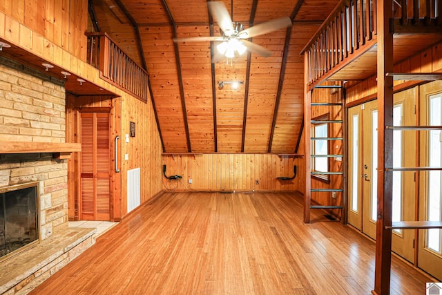 unfurnished living room with a fireplace, wooden walls, wooden ceiling, and light wood-type flooring