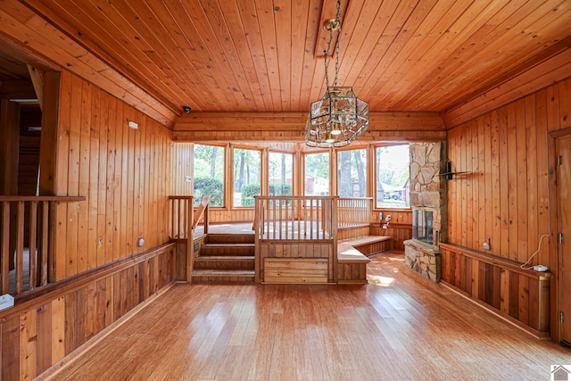 interior space with a notable chandelier, wooden walls, light hardwood / wood-style flooring, and wood ceiling