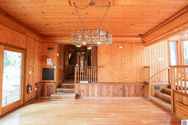 interior space featuring a notable chandelier, hardwood / wood-style flooring, wooden ceiling, and wooden walls