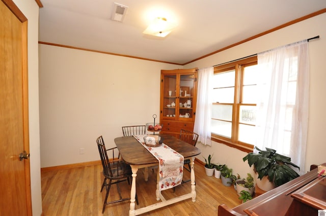 dining space featuring ornamental molding and light hardwood / wood-style flooring