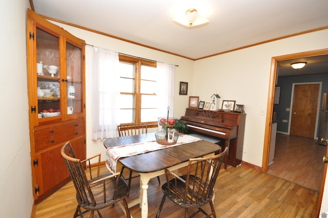 dining area with ornamental molding and light hardwood / wood-style flooring