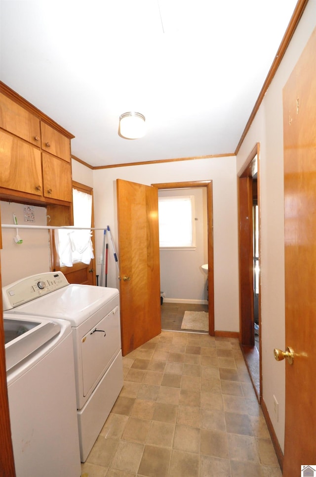 clothes washing area featuring crown molding, cabinets, and washing machine and clothes dryer