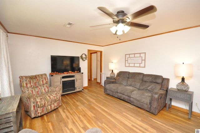 living room with ceiling fan, ornamental molding, and light wood-type flooring