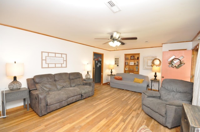 living room with light hardwood / wood-style floors, ornamental molding, and ceiling fan