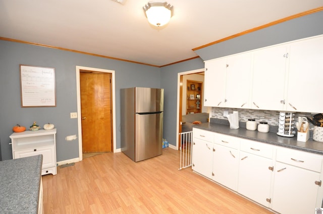 kitchen with stainless steel fridge, crown molding, light wood-type flooring, white cabinets, and tasteful backsplash