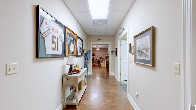 hall with concrete floors and a drop ceiling