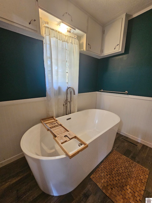 bathroom featuring a textured ceiling, a tub to relax in, and hardwood / wood-style flooring